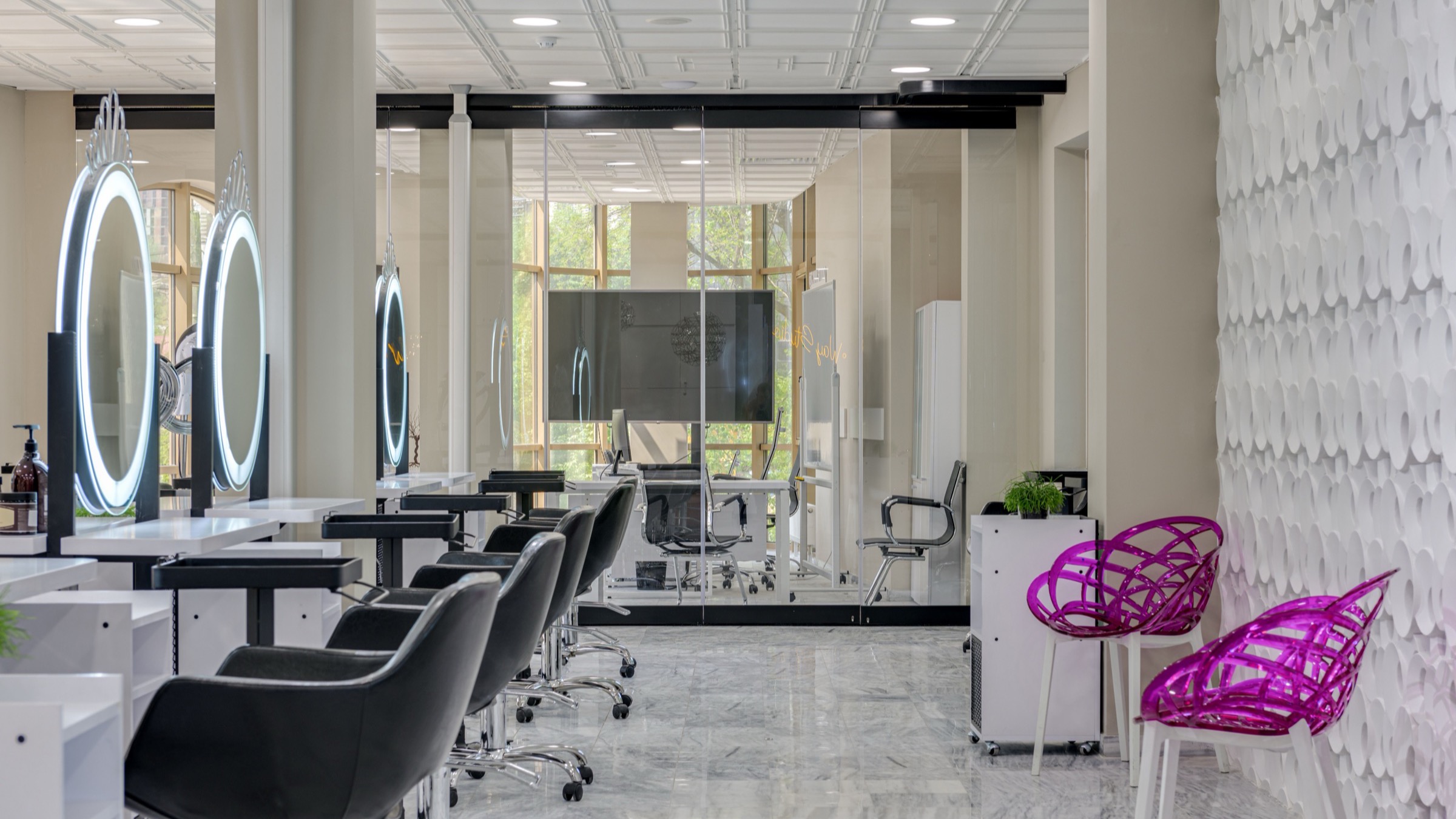 A modern salon interior with lit mirrors and styling chairs